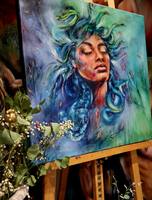 „Medusa“ auf einer Holzstaffelei, davor getrocknete Zweige mit kleinen Blüten.